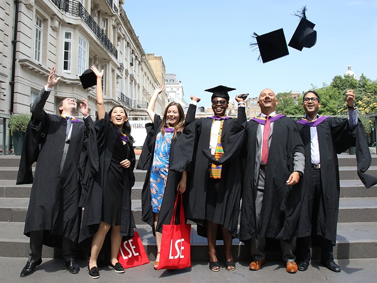 A group of LSE alumni toss mortar boards in celebration