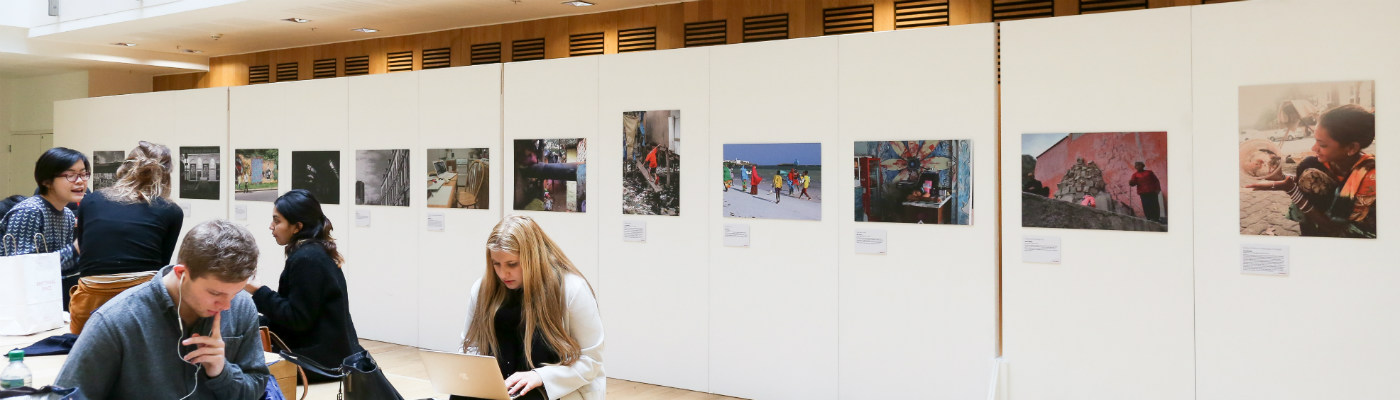 A gallery space with photographs displayed and students sitting around.