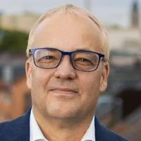 Jens Beckert headshot. He is wearing glasses, a white shirt and a blue suit jacket.