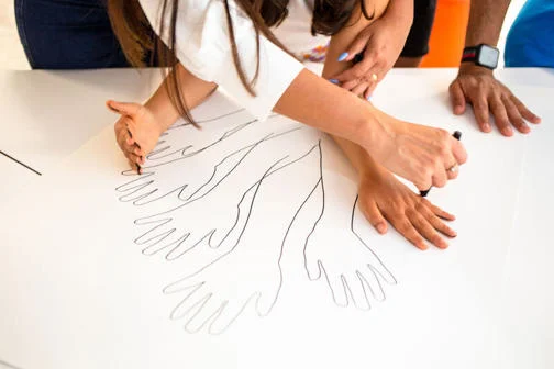 Children drawing outlines of their hands and arms