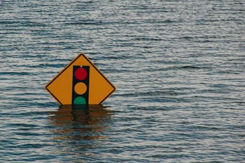 A street sign with a stop light sign submerged in flood waters