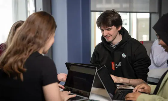 Student working on laptop with other students