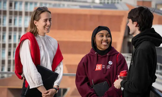 Three students standing together laughing