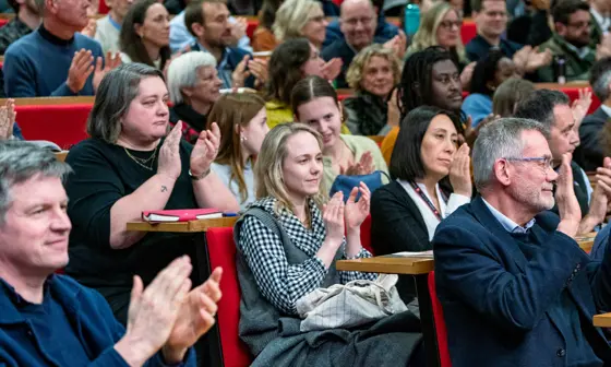 rows of people clapping, seated in a lecture theatre