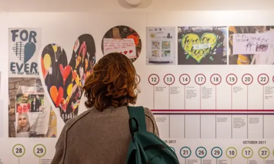 A photo of a woman looking at a Grenfell Tower exhibition