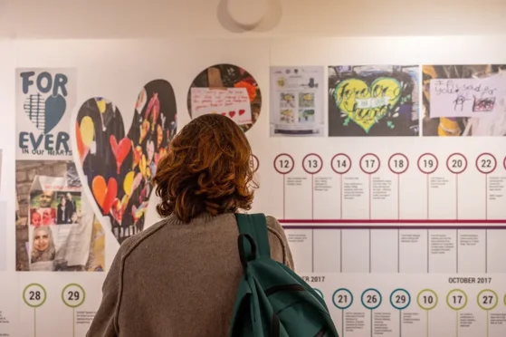 A photo of a woman looking at a Grenfell Tower exhibition