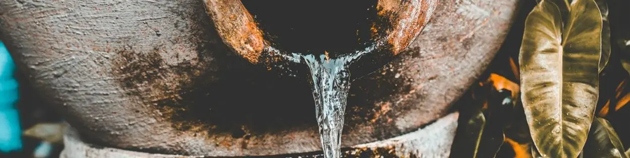 An outdoor water tank spilling water.
