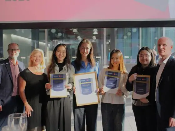 A group of four geography students posing with their certificates next to Chronos judges.