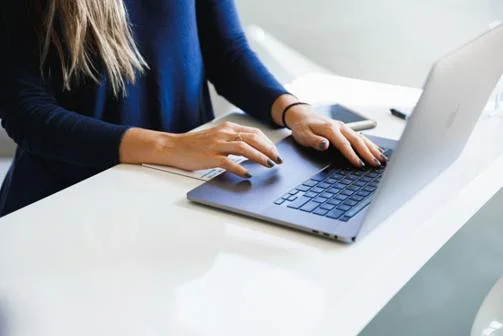Laptop and hands with blue nail varnish. Photo by Luke Southern on Unsplash