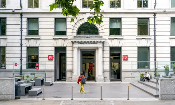 Student walking in front of LSE building wearing backpack