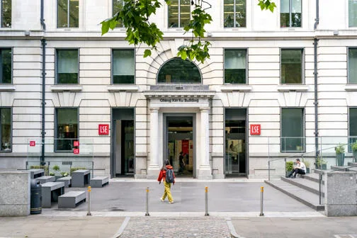 Student walking in front of LSE building wearing backpack