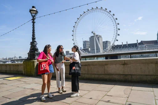 LSE students talking near the Thames with the London Eye in the background
