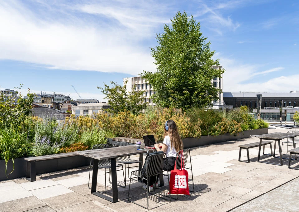A student working on LSE rooftop with an LSE totebag
