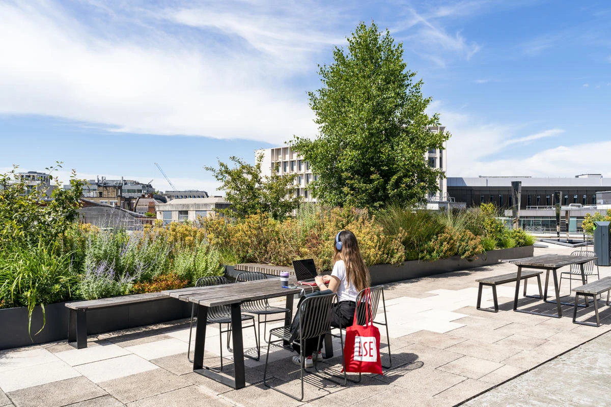 A student working on LSE rooftop with an LSE totebag