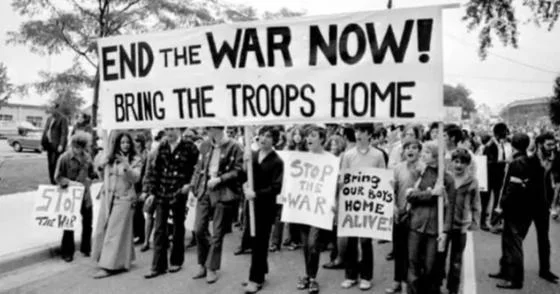 Crowd holding up the sign "End the war now! Bring the troops home" during a protest.
