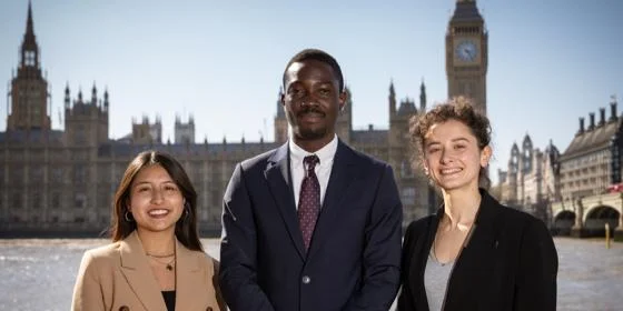 Three students in front of the Houses of Parliament