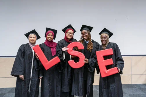 LSE Widening Participation Pathways to Law participants in graduation gowns and caps holding large red LSE letters