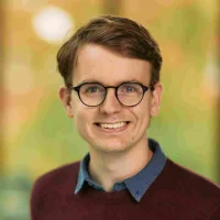 Headshot of a man with glasses smiling at the camera