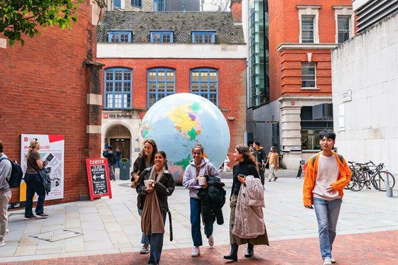 Students walking on campus in front of "The World Turned Upside Down" sculpture.