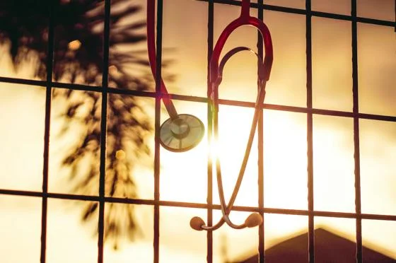 A stethoscope hanging on a window bar in a sunset.