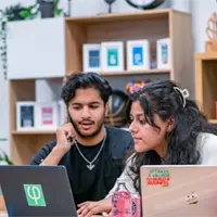 man and woman talking with two laptops in front of them