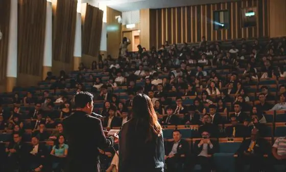 Two speakers giving a lecture to a full audience