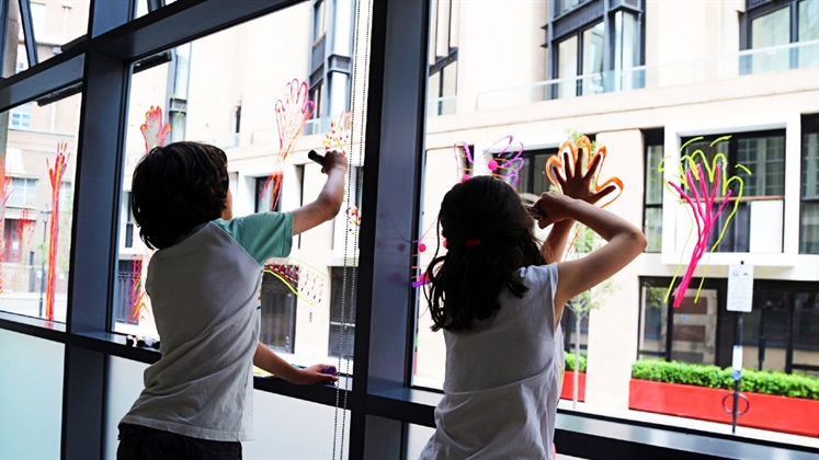 Two children drawing on a window