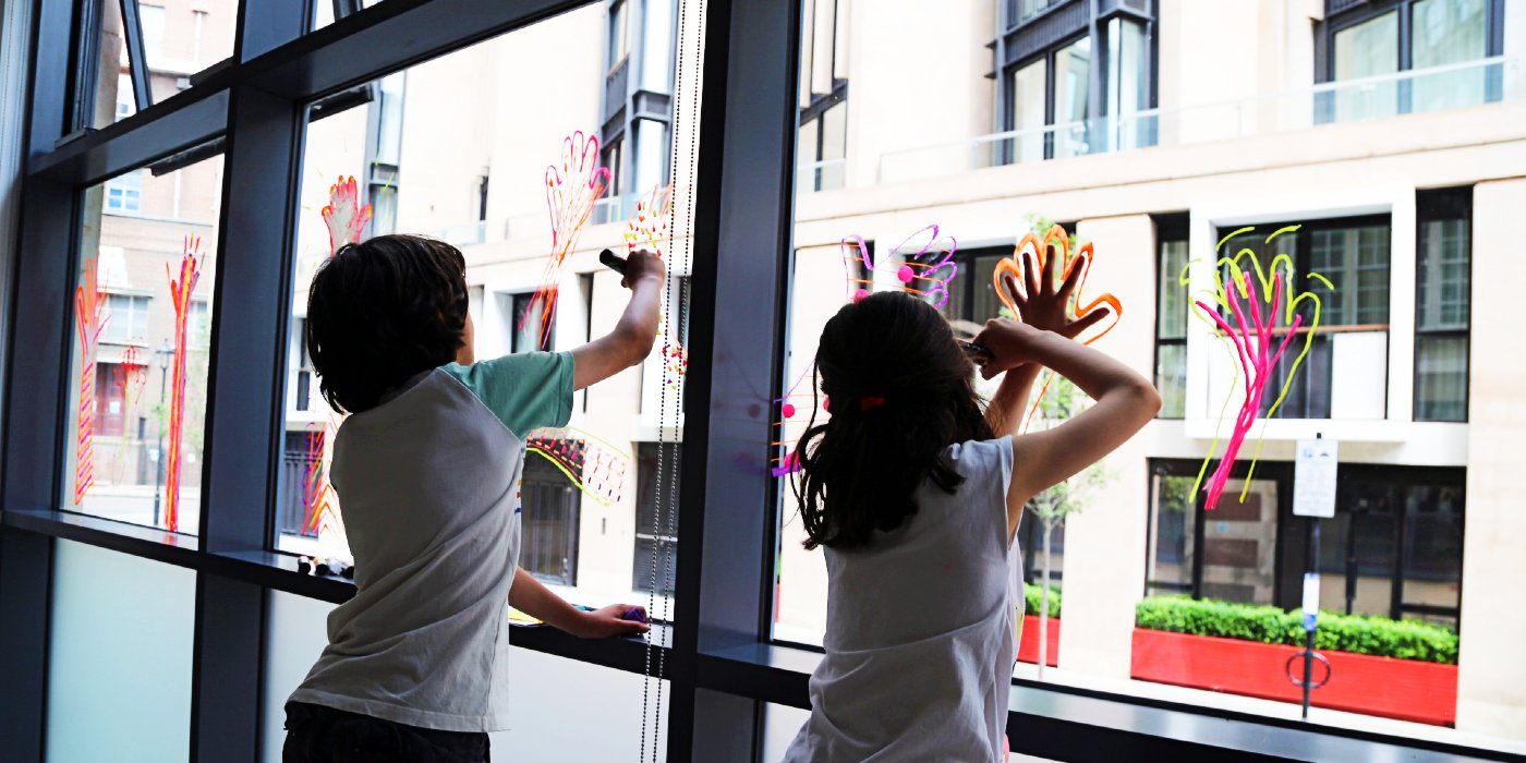 Two children drawing on a window
