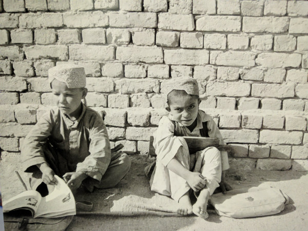 Young boys sat against a wall