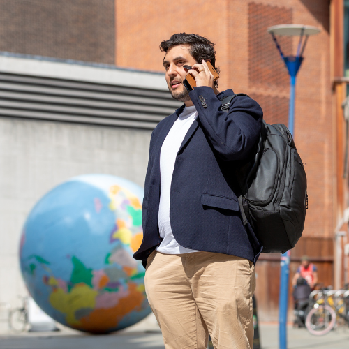 Mature student talking on the phone in a blazer in front of a globe