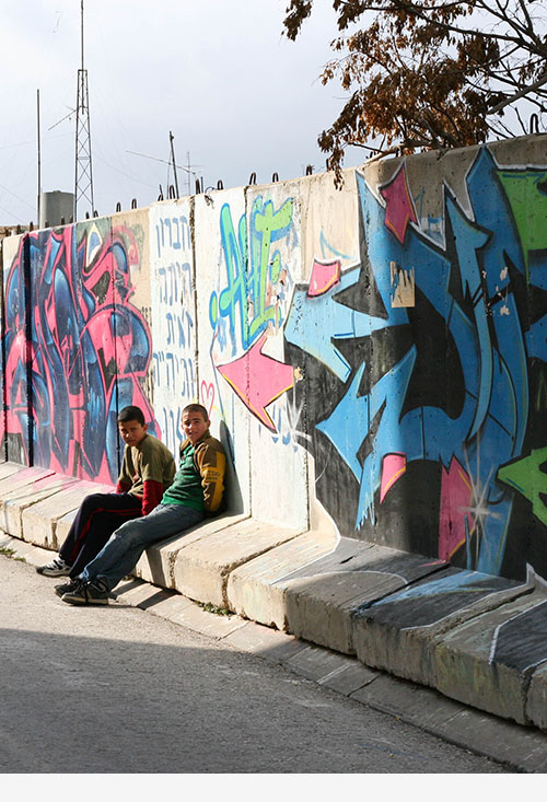 Palestinian boys sitting in front of wall