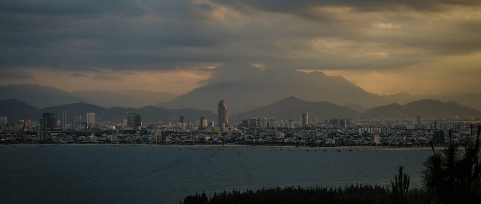 A cloudy view over a bay with mountains at sunset