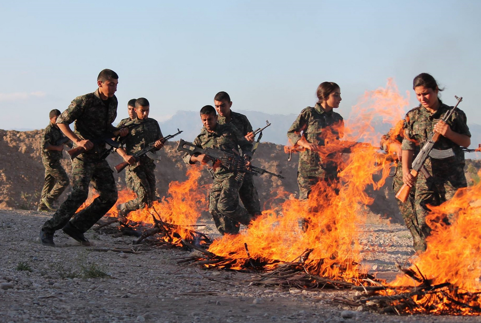 Jihadi soldiers in a desert by burning piles of wood