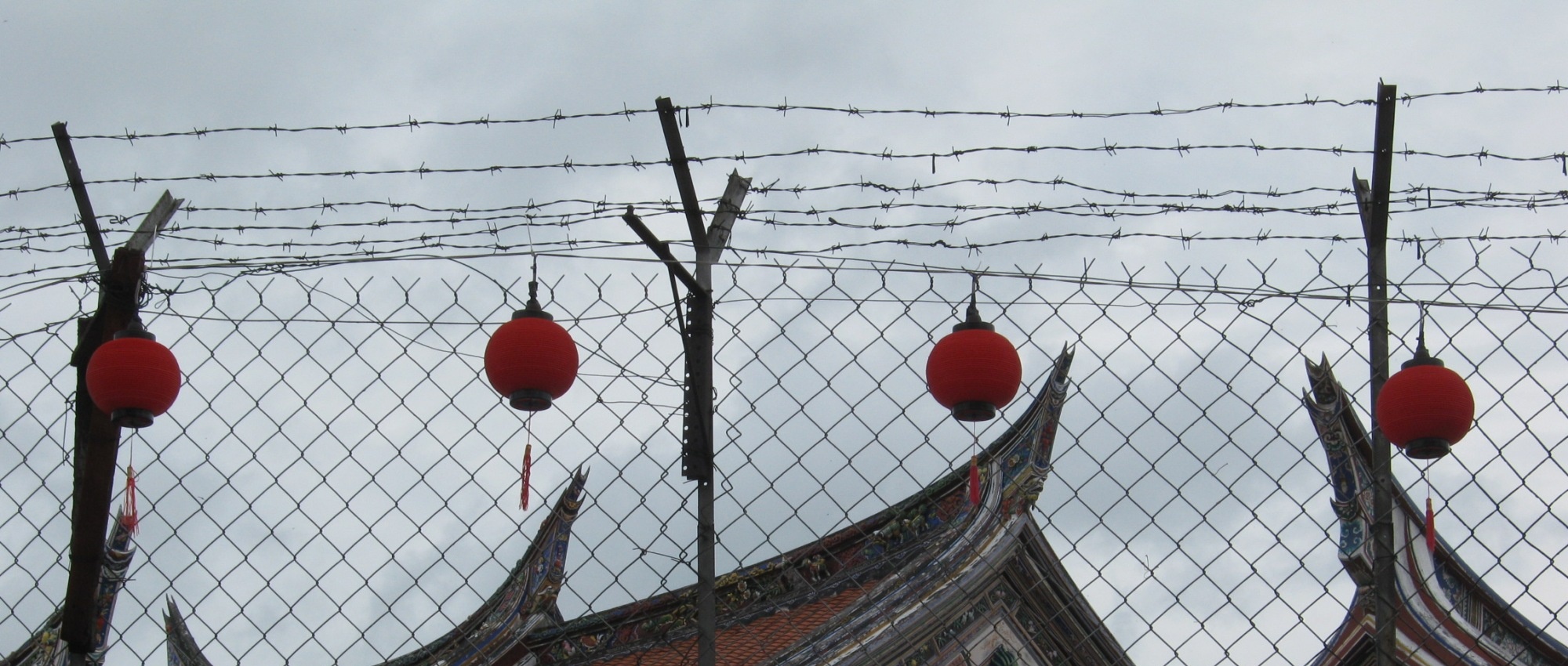 Red lanterns hanging on a barbed wire fence