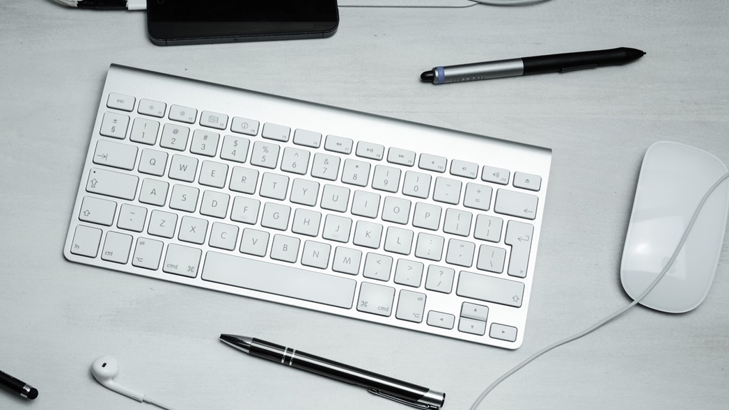 A keyboard, pens and a mouse on a desk
