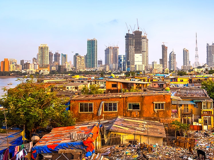 A slum suburb is overshadowed by the city skyscrapers beyond