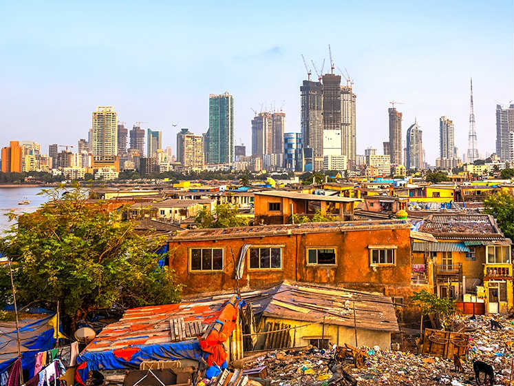 A slum suburb is overshadowed by the skyscrapers beyond