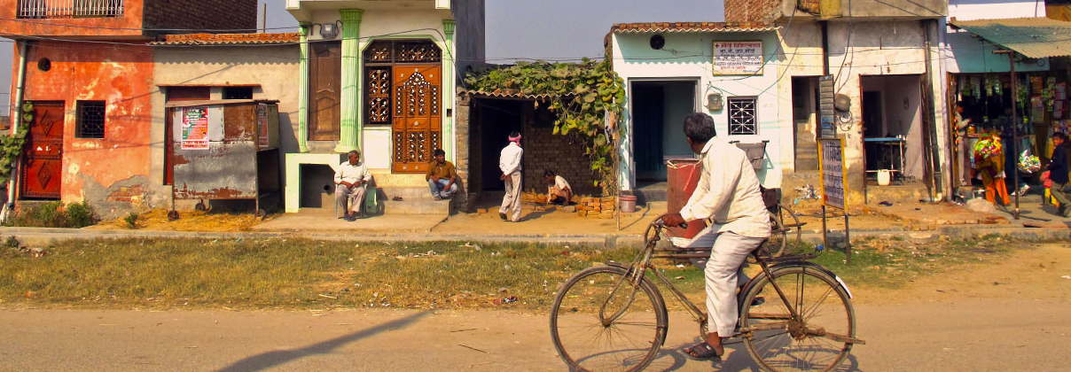 Man ridding bicycle on street rural India