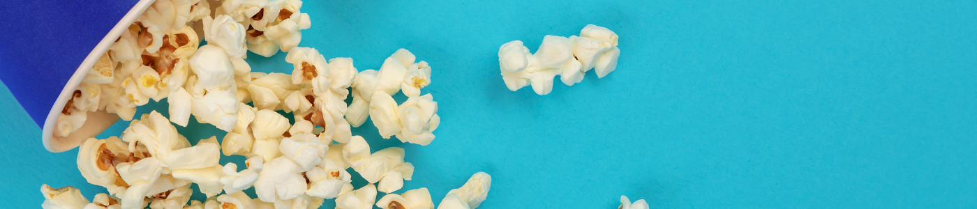 Spilt popcorn on bright blue background_Standard Banner_sourced via Canva