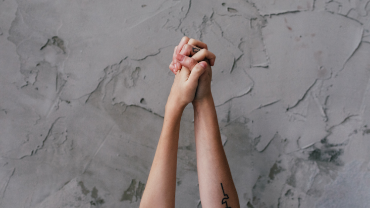 Two hands held together in air against concrete background