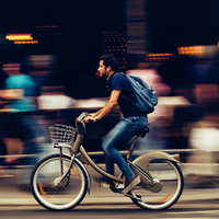 Man riding bike along busy city street_200x200_sourced via Canva