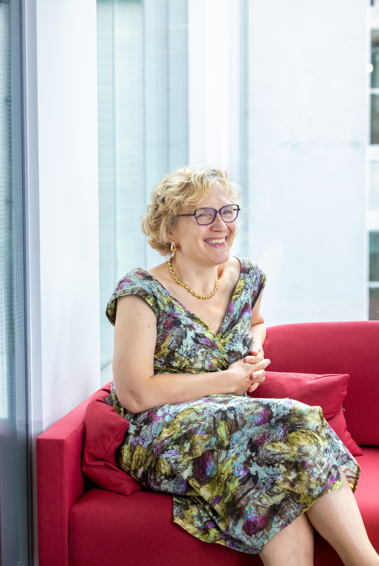 Elizabeth Holden, a blonde woman in glasses, smiling beyond the camera