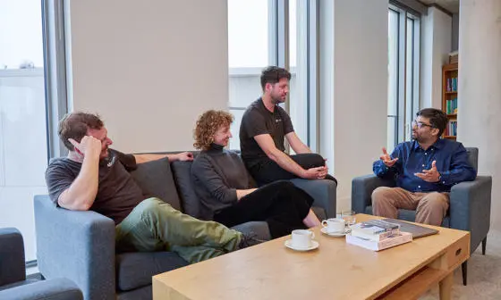 4 people sitting on sofas chatting to one another in an office