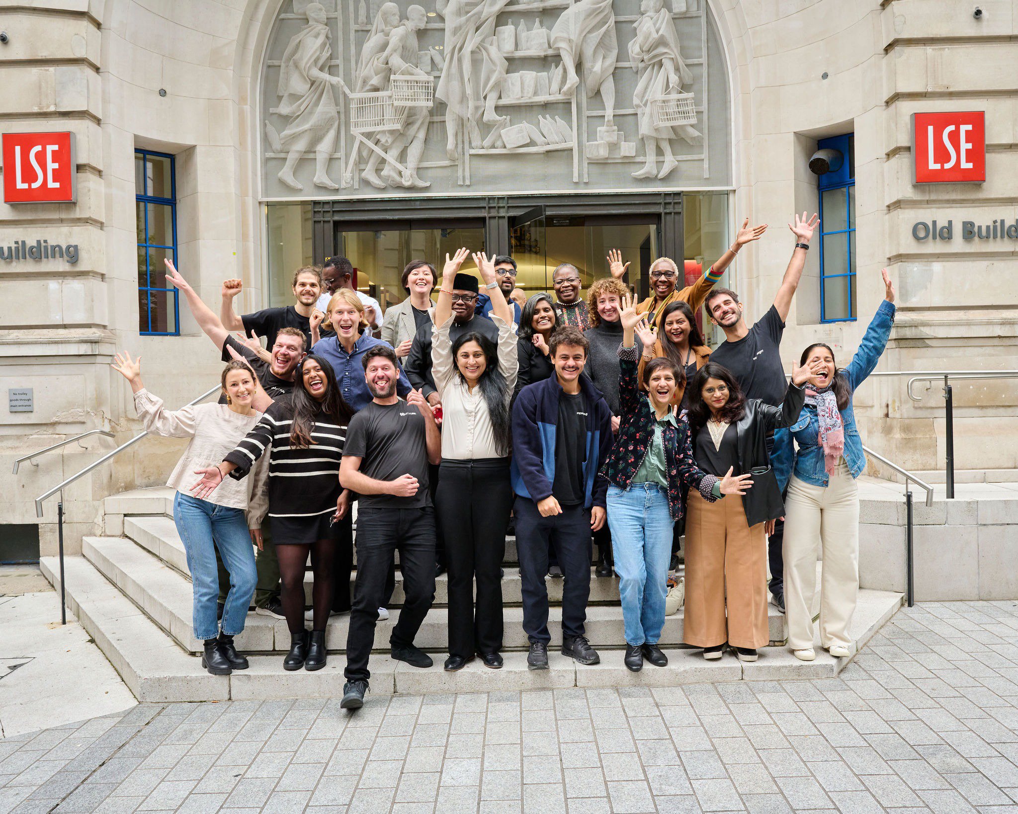 Group of people with the hands raised posing outside the LSE Old Building