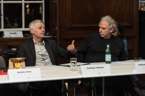 One man speaking and a second man watching him