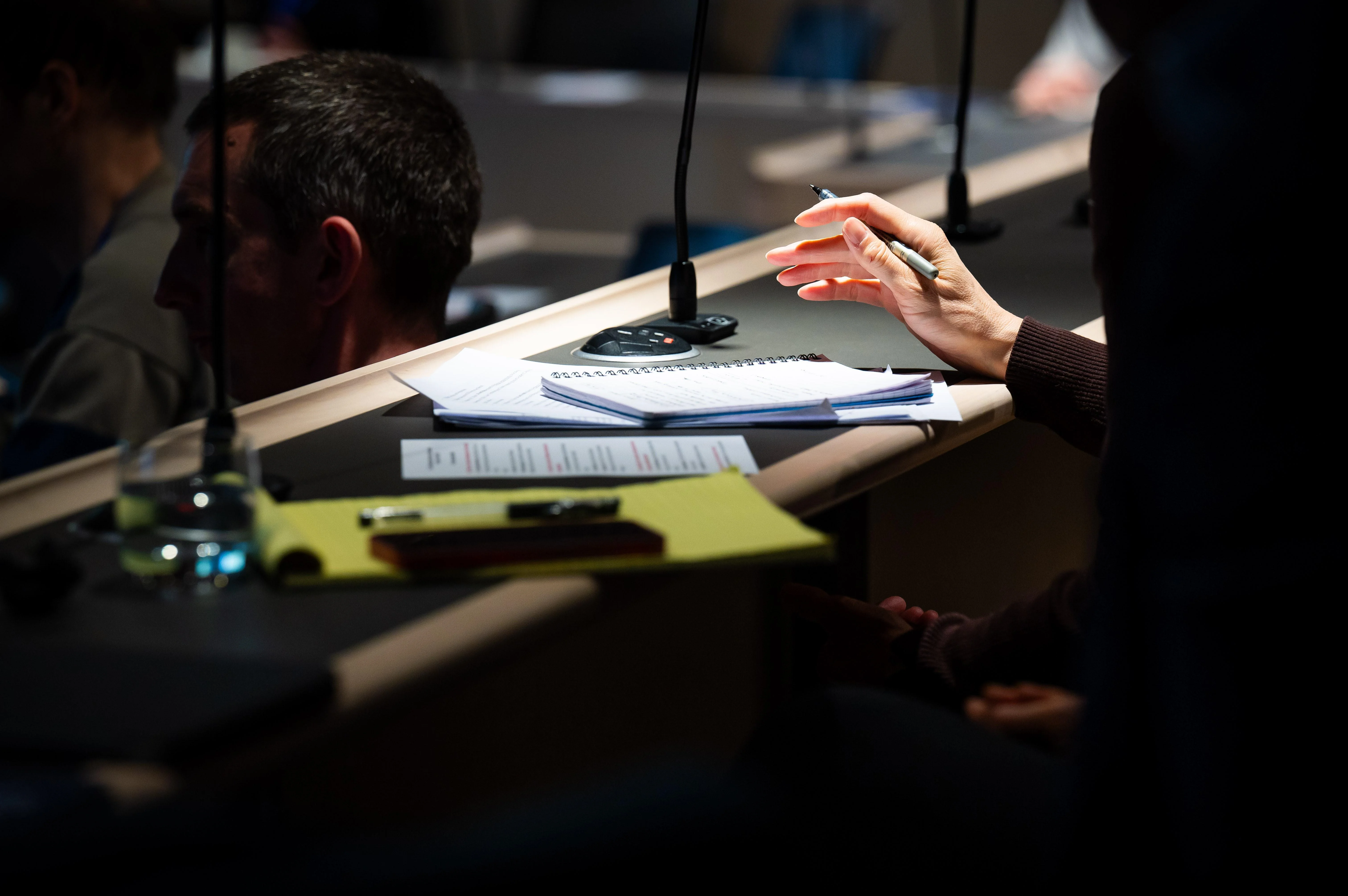 A hand holding a pen poised to take notes in a notebook.
