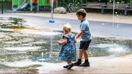 two children playing in a fountain installation