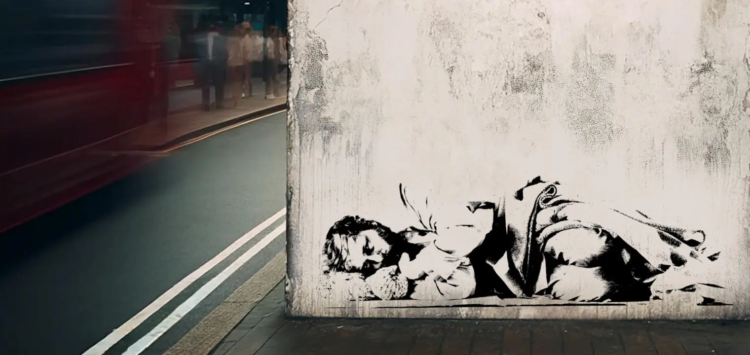 A Banksy-style graffiti of a homeless person on a wall in London