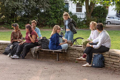 Young people sit in a park and laugh