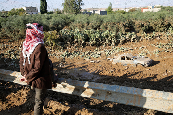 A person stands looking at a car half submerged by floods in Jordan. 